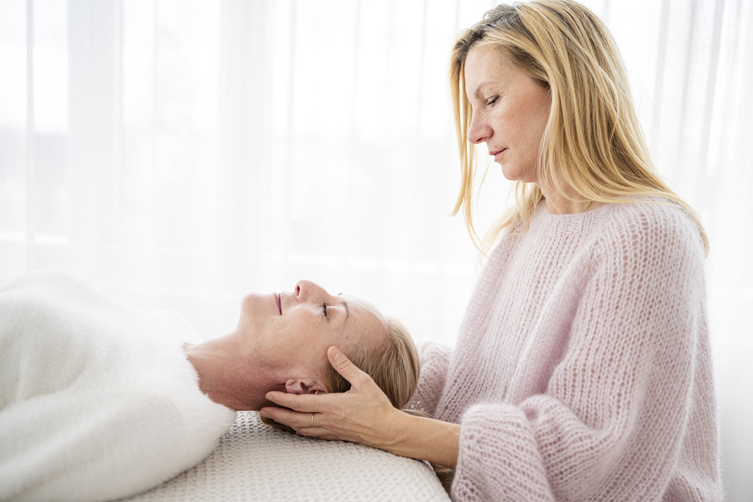katharina-baehner-neigt-den-kopf-einer-patienten-beim-durchfuehren-der-craniosacralen-therapie